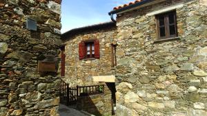 un edificio de piedra con una ventana roja. en Casa Da Pena, en Góis