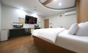 a bedroom with a bed and a desk with a tv at Hotel Feel Green in Goyang