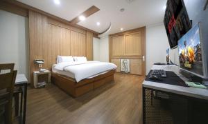 a bedroom with a bed and a desk with a computer at Hotel Feel Green in Goyang