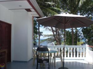 a table and chair with an umbrella on a balcony at Villa Juana in Panglao