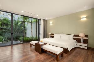 a bedroom with a white bed and a large window at Flamingo Dai Lai Resort in Ngọc Quang