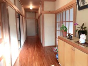 un couloir vide avec parquet et une chambre avec fenêtres dans l'établissement 花源, à Beppu