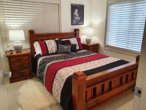 Un dormitorio con una gran cama de madera con almohadas en Bed and Breakfast en Cooranbong