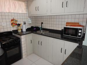a small kitchen with a microwave and a sink at Solitaire Guest Apartments in Pretoria