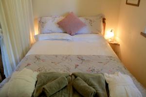 a bed with pillows and towels on top of it at The Nest - Thatched seaside country cottage for two in Stokeinteignhead