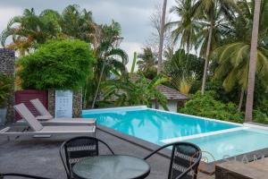 a pool with chairs and tables and palm trees at OG Villa & Private Pool in Koh Samui