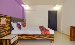a bedroom with a bed with a wooden headboard at FabExpress Kohinoor Residency in Pune