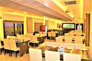 a dining room with tables and white chairs and tablesktop at Sambhabana Hotel & Suites in Tarapith