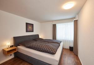 Schlafzimmer mit einem Bett und einem Fenster in der Unterkunft Residence Eden in Arosa
