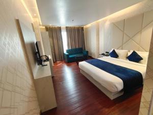 een hotelkamer met een bed en een stoel bij The Emerald Hotel & Siya Milan Banquets in Muzaffarpur