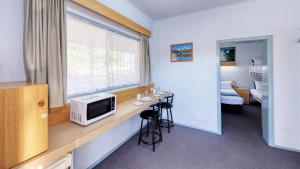 Zimmer mit einem Schreibtisch, einer Mikrowelle und einem Fenster. in der Unterkunft Tumut Farrington motel in Tumut