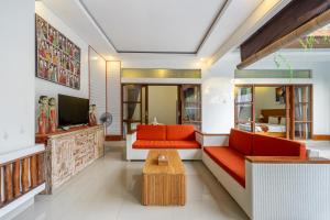 Il comprend un salon doté d'un mobilier orange et d'une télévision. dans l'établissement De Gani, à Seminyak