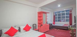 Un dormitorio con una cama con almohadas rojas y una ventana en A.P.S. Lodge en Darjeeling