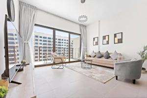 a living room with a couch and a large window at StoneTree - Spacious 2BR Apartment in Golf Views Block A in Dubai