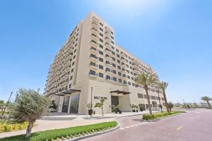 un gran edificio blanco con una carretera delante en StoneTree - Spacious 2BR Apartment in Golf Views Block A en Dubái