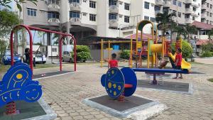 two children playing on a playground in a park at Cuti Cuti apartment Glory Beach in Port Dickson