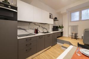a kitchen with white cabinets and a dining room at Easylife - Tranquillo studio vicino Prada in Milan
