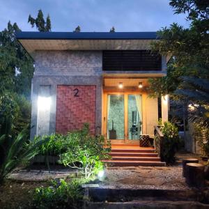 uma casa de tijolos com uma porta da frente e escadas em Baan Pak Arom Resort Chanthaburi 