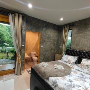 um quarto com uma cama grande e uma janela grande em Baan Pak Arom Resort Chanthaburi 