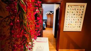 un couloir avec un bouquet de fleurs rouges sur un mur dans l'établissement Casa Simona, à Villaviciosa