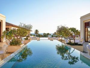 a swimming pool in a resort with chairs and trees at Grecotel Kos Imperial in Kos Town