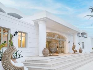 une maison blanche avec 2 chaises en osier sur une terrasse couverte dans l'établissement Grecotel Casa Paradiso, à Marmari