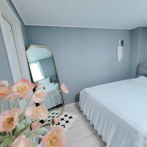 una camera con letto, specchio e fiori di Goose Stay a Bucheon
