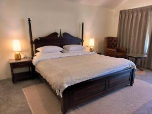 a bedroom with a large bed with two lamps and a chair at Dev Bhoomi Farms & Cottages in Dharamshala