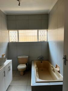 a bathroom with a tub and a toilet and a sink at BDN Backpackers in Johannesburg