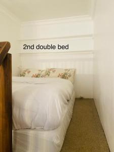 a bed with white sheets and double bed at Large self-contained cozy studio in London