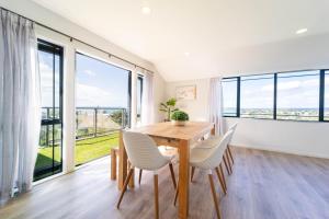 a dining room with a table and chairs and large windows at Family Friendly Oceanview Howick Home - Pets+ in Auckland