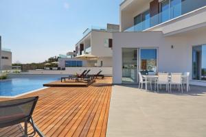 a wooden deck with chairs and a table on a house at Sea Pearl Luxury Beachfront Villas in Ayia Napa