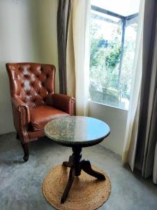 a table and a chair in a room with a window at Dev Bhoomi Farms & Cottages in Dharamshala