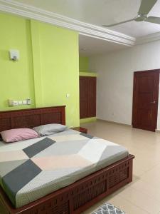 - une chambre avec un grand lit aux murs verts dans l'établissement AGIMVILLA 05, à Golo-Tokpa