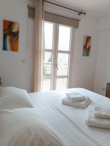 Una cama blanca con dos toallas encima. en Aphrodite Hills Adonis Apartment, en Kouklia