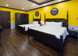 two beds in a room with yellow walls and wooden floors at Charming beauty hotel in Da Nang