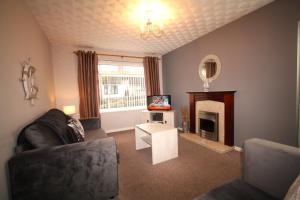 a living room with a couch and a fireplace at Heulwen - Moelfre in Moelfre