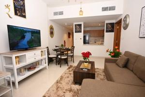 a living room with a couch and a tv and a table at Sunshine pool view 1BR apartment in Abu Dhabi