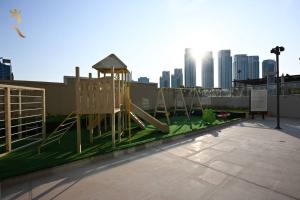 a playground with a slide and a chair in a city at Sunshine pool view 1BR apartment in Abu Dhabi