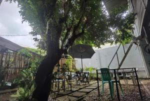 einen Tisch und Stühle unter einem Baum mit einem Sonnenschirm in der Unterkunft Royal Duchess Pension in Puerto Princesa