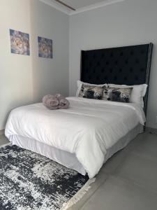 Schlafzimmer mit einem großen weißen Bett mit einem schwarzen Kopfteil in der Unterkunft Ju’s Self-catering Accommodation in Okakarara