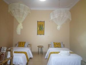 um quarto com duas camas e dois lustres em Lycklama Guesthouse em Jinja