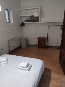 a bedroom with a white bed with two towels on it at San Isidro Labrador, apartamento en Las Vistillas junto a metro Puerta de Toledo in Madrid