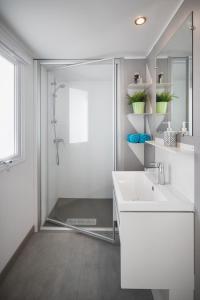 een witte badkamer met een wastafel en een douche bij Camping Marvilla Parks Friese Meren - Roan in Wijckel
