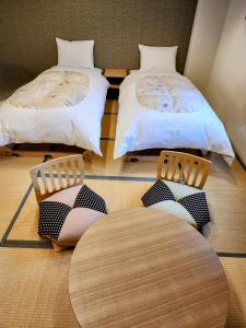 a room with two beds and a table and chairs at Hakuba Hotel Hana-no-Sato in Hakuba