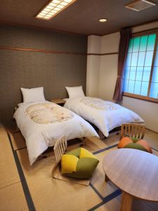 a room with two beds and a table and chairs at Hakuba Hotel Hana-no-Sato in Hakuba
