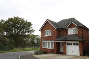 a red brick house with a white garage at Spacious home with office and double driveway & FREE Wifi By ULTIMATE HOMES AWAY in Winnersh