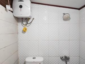 a white tiled bathroom with a toilet and a camera at Arafah Resort @ Danau Kerinci Jambi RedPartner in Hiang
