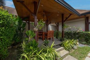 a patio with a table and chairs under a wooden pergola at VILLA ADONARA | Private Pool | Kokyang Estate by Tropiclook | Nai Harn beach in Nai Harn Beach
