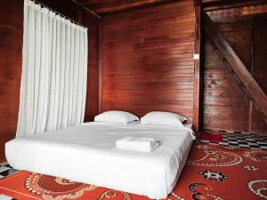 a bed in a room with a wooden wall at Arafah Resort @ Danau Kerinci Jambi RedPartner in Hiang +30 photos